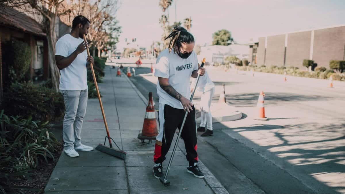 A group of volunteers cleaning a city sidewalk during the day, showcasing community spirit and teamwork.