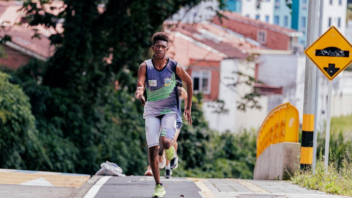 Athletic man running on urban street pathway, focused on exercise amidst city background.