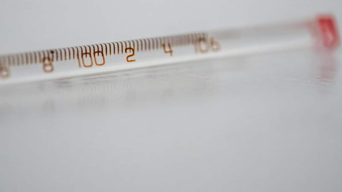 Detailed close-up of a mercury glass thermometer on a white surface, showing temperature measurements.