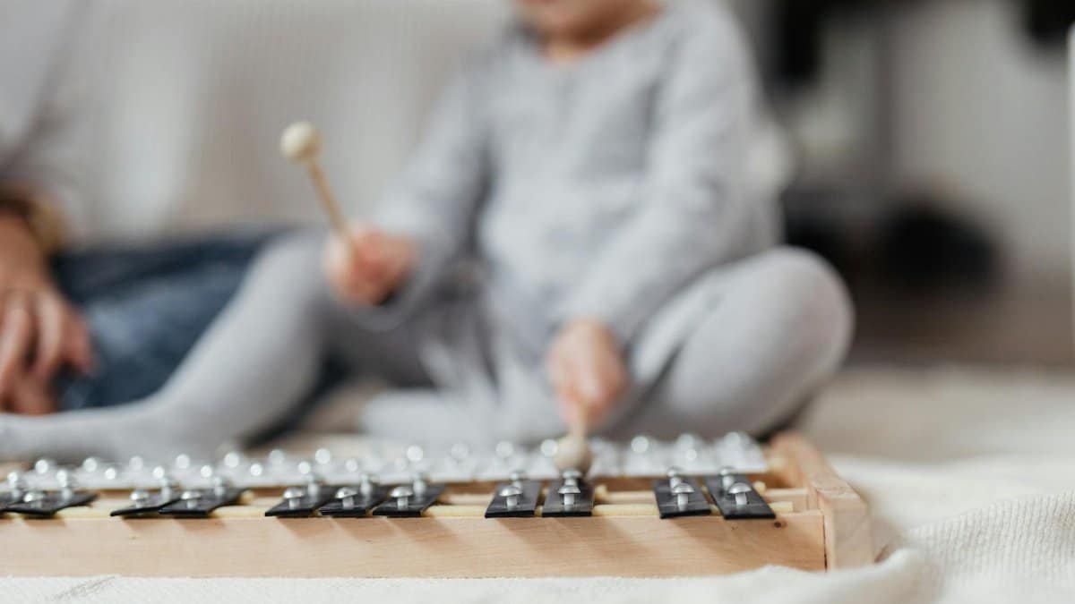 A young child playing a xylophone on a soft blanket indoors, showcasing musical exploration.