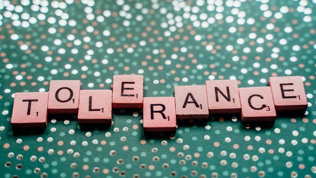 Close-up of scrabble tiles spelling 'tolerance' on a turquoise background.