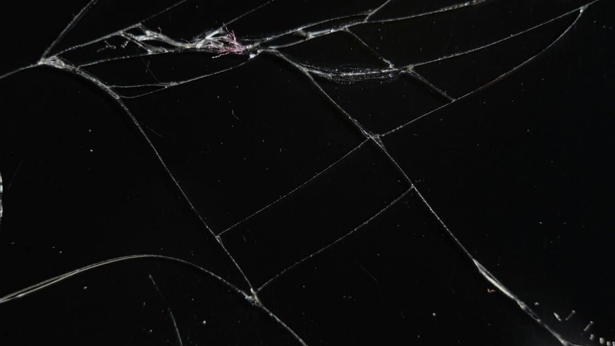 Close-up of a cracked glass surface displaying intricate patterns and reflections.