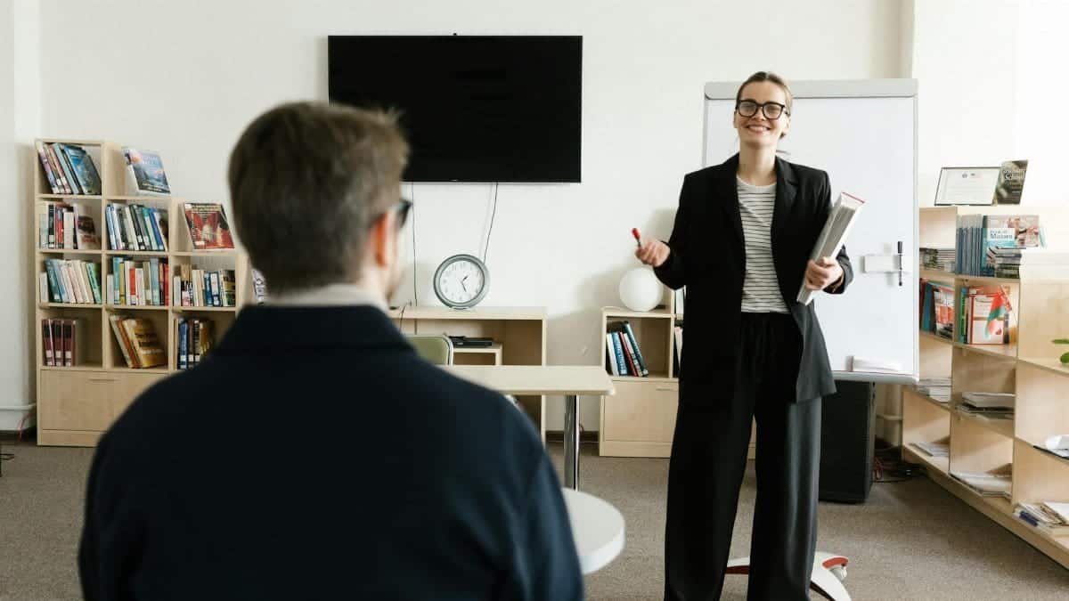 Businesswoman giving presentation in office with bookshelves and clock.