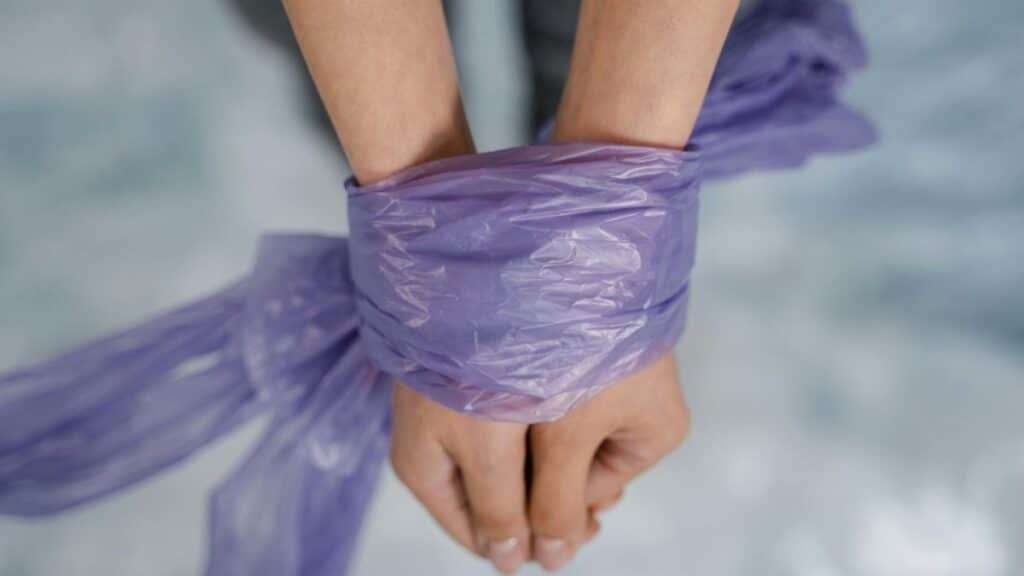 Hands bound with purple plastic in a close-up view conveying restriction and bondage.