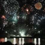 Dazzling fireworks display over Vancouver's waterfront at night, reflecting on the water.
