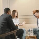 A couple engaging in a heated discussion during a therapy session with a therapist.