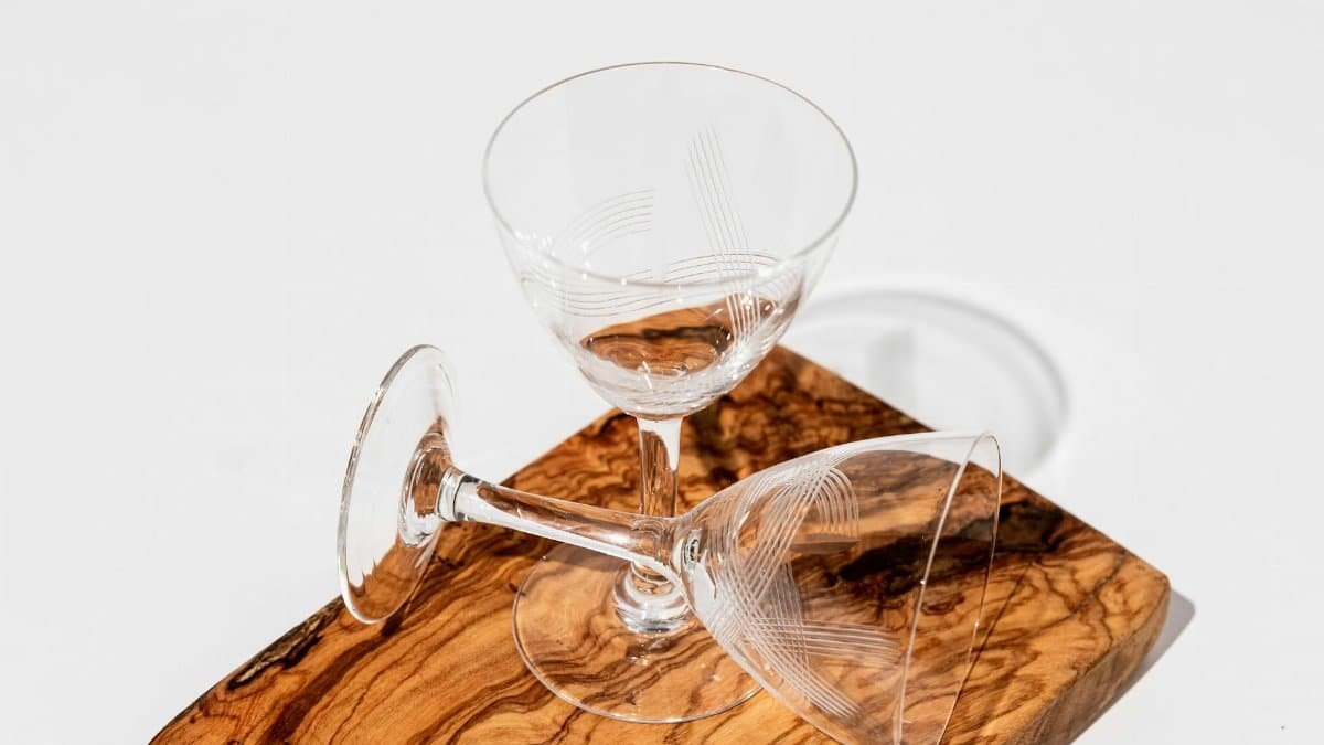 Two empty crystal glasses on a wooden board with a minimalist design, perfect for decor ideas.