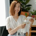 Cheerful woman at home showcasing a tie-dye technique with fabric.