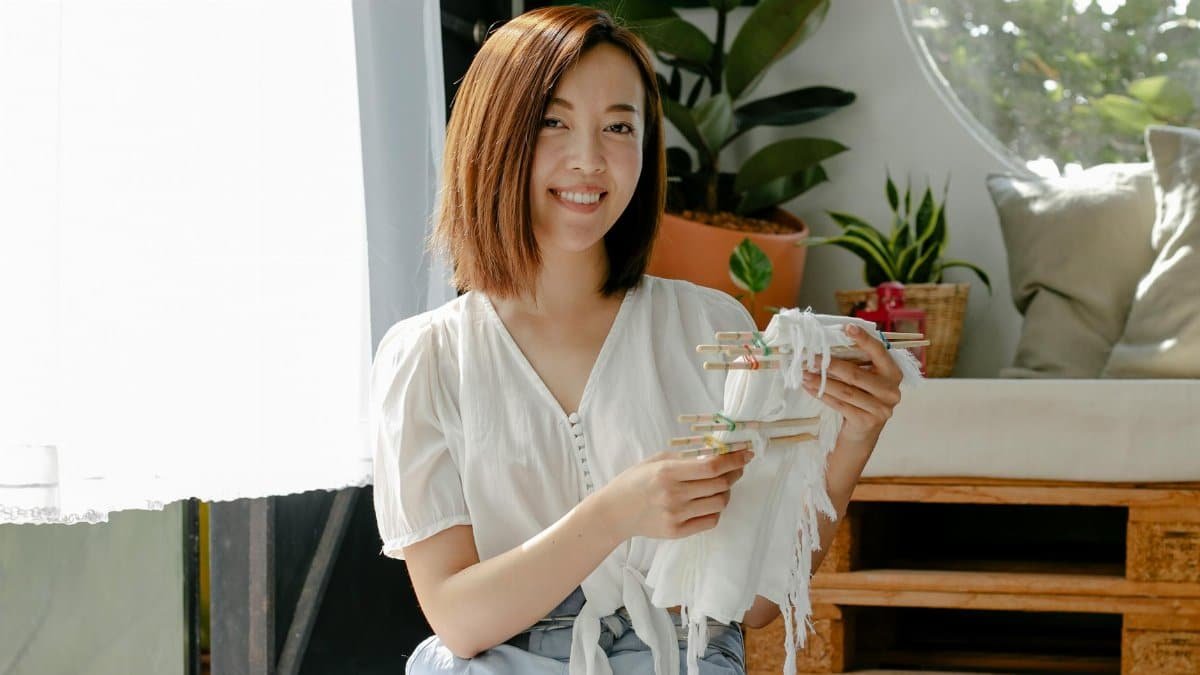 Cheerful woman at home showcasing a tie-dye technique with fabric.