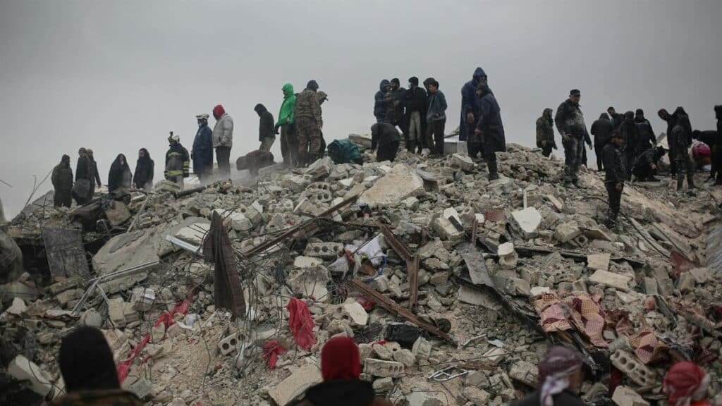 Survivors and rescuers search through rubble after a disaster in Idlib, Syria.