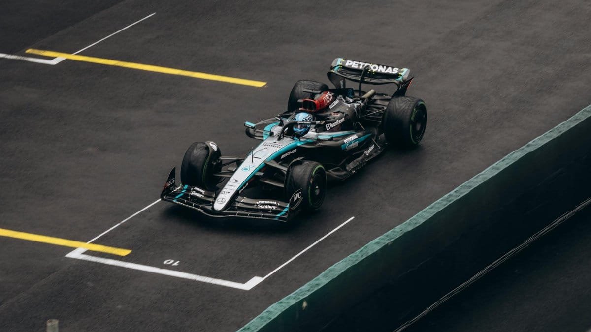 Dynamic shot of a Formula One car racing on wet asphalt, showcasing speed and precision.