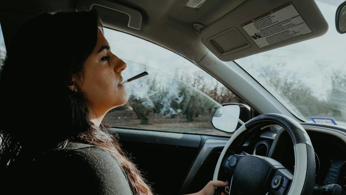 Woman driving and smoking, concentrating on the road. Social issues theme.