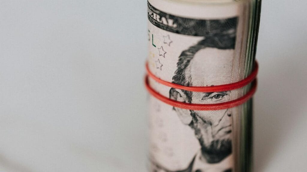 Close-up of a roll of US dollars wrapped with a red rubber band focusing on financial abundance.