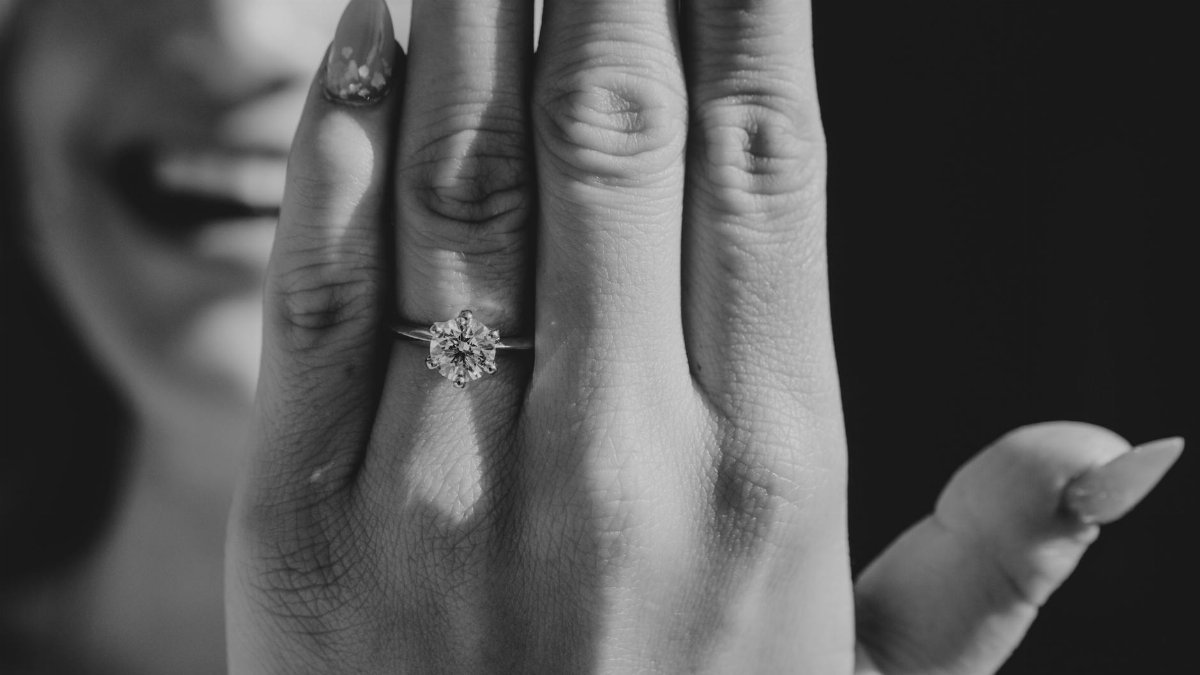 Close-up of woman's hand displaying engagement ring, exuding happiness.