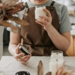 A woman crafting candles in a rustic workshop, focusing on scents and quality.