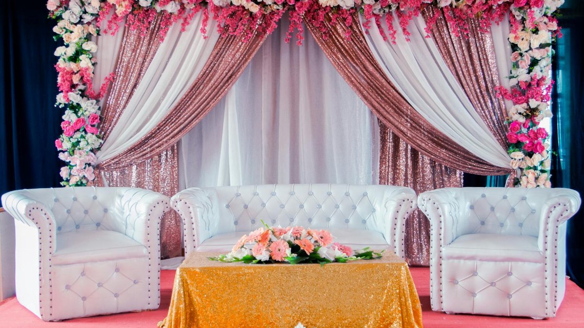 Beautiful wedding stage setup with white sofas and vibrant floral decorations, ideal for weddings.