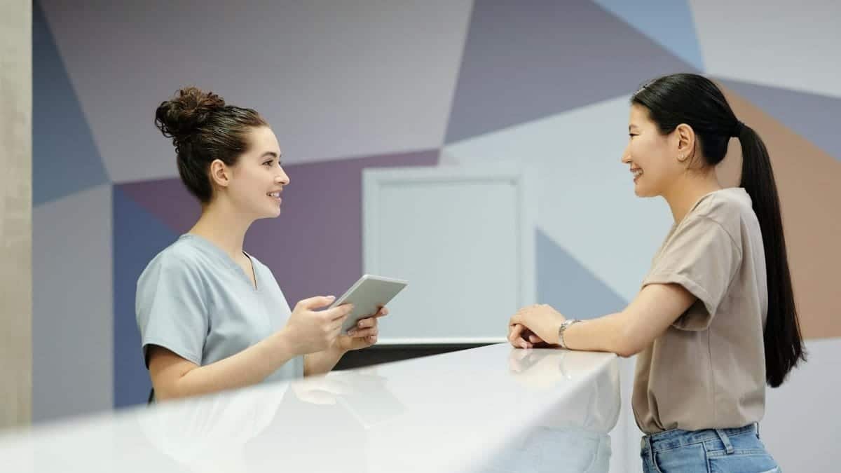 A receptionist and a visitor engaging at a modern reception desk, indoors.