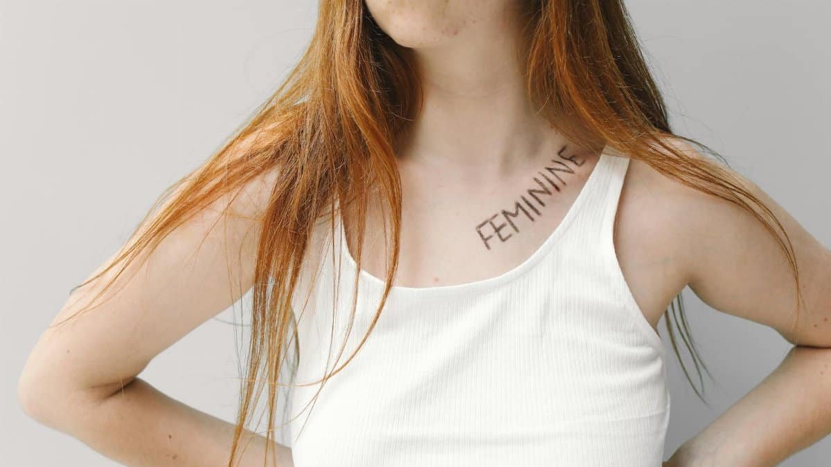 Portrait of a young woman with the word 'feminine' written on her collarbone, expressing individuality and empowerment.