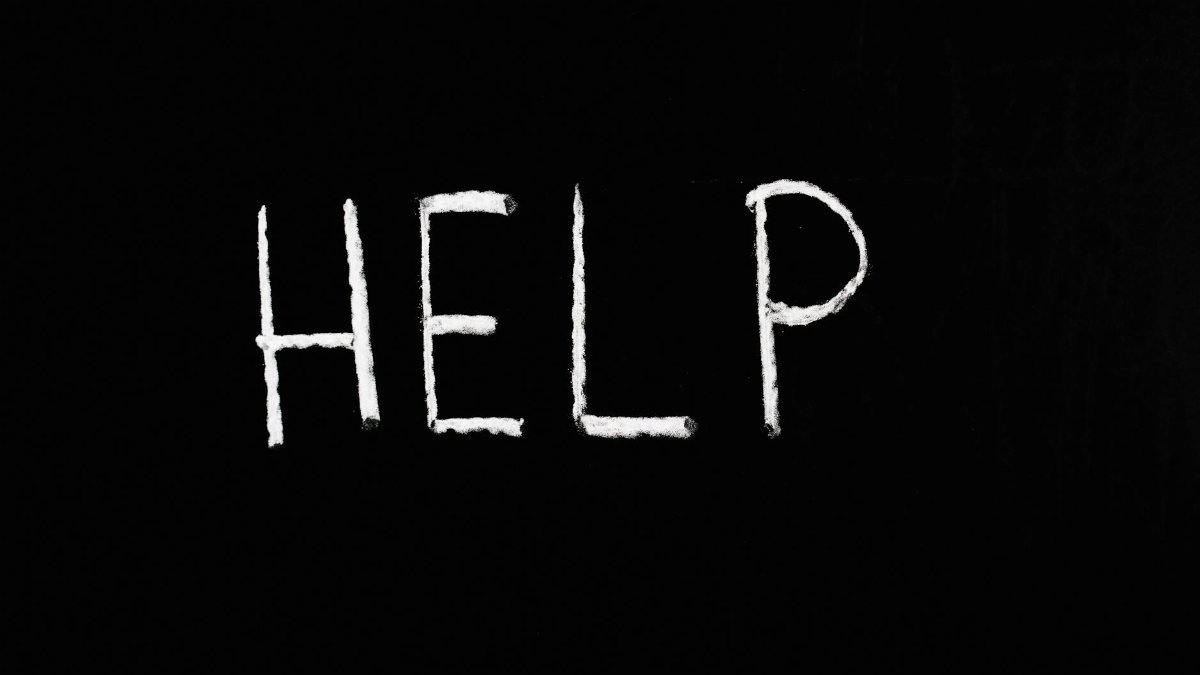 Chalk-written 'HELP' on a deep black background symbolizes assistance and encouragement.