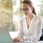 Confident businesswoman using a laptop at her desk, focused on her work.