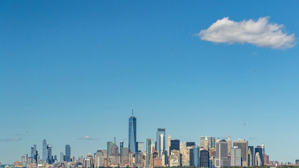 Stunning view of New York City skyline featuring the iconic One World Trade Center under a clear blue sky.