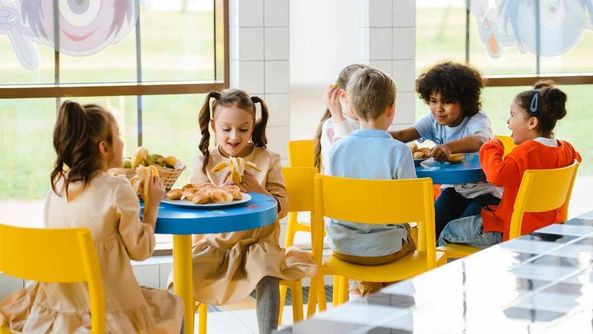 Group of children eating together at a school cafeteria, sharing joy and food.