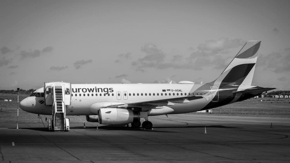 A Eurowings airplane parked on the tarmac with external stairs attached, in black and white.