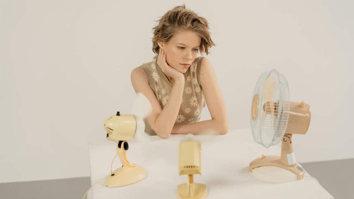 Thoughtful woman in a studio setting with vintage electric fans on display