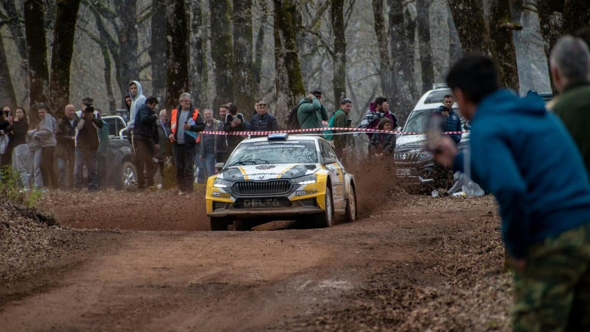 Exciting rally car event with spectators on a dirt track in Ilia, Greece, showcasing motorsport action.