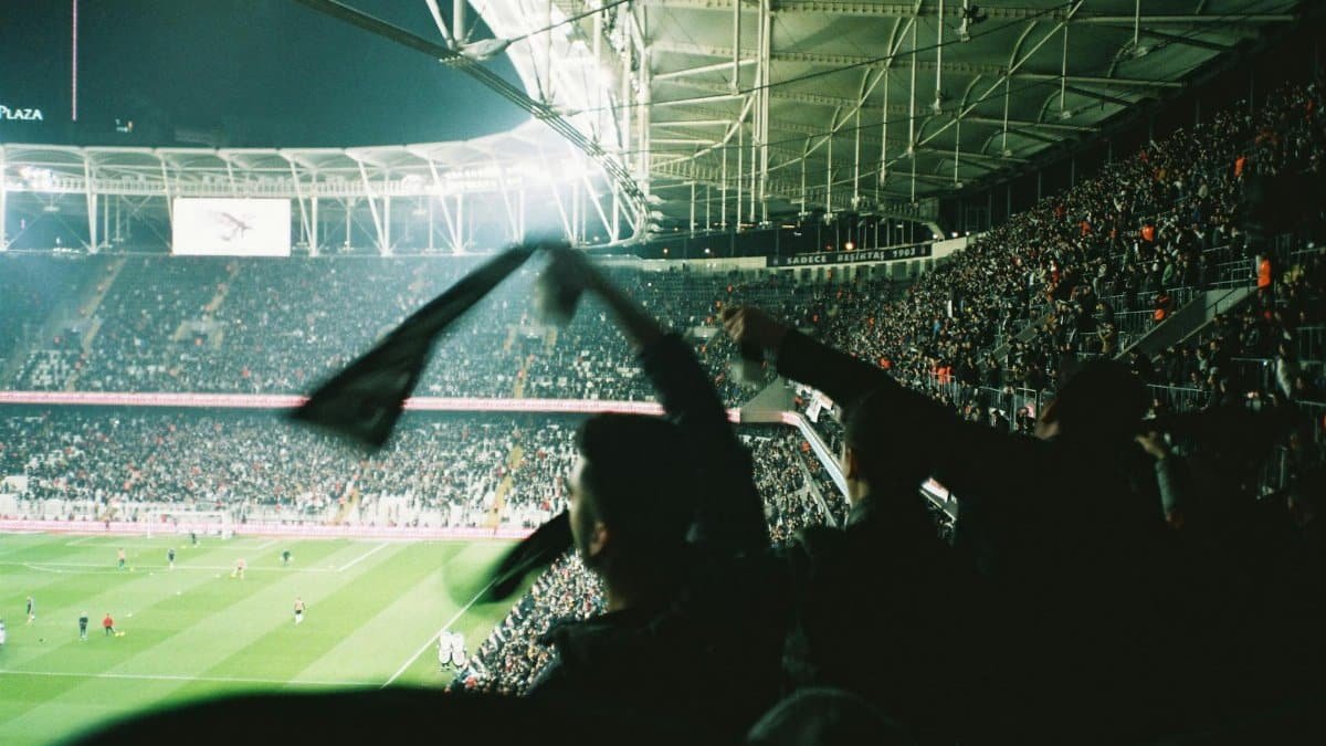 Exciting night soccer match with cheering fans in a brightly lit packed stadium.