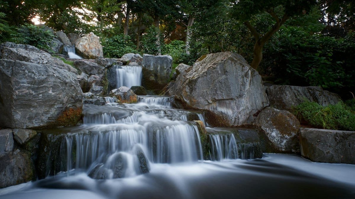 Long-exposure capture of a tranquil waterfall flowing over rocks in a peaceful forest park.