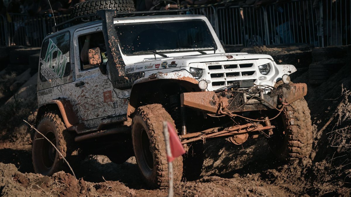A rugged off-road vehicle navigating a challenging muddy terrain during the day.