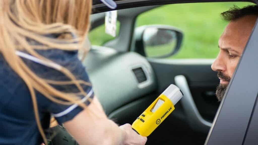 Police officer administering a breathalyzer test to a driver in a car, ensuring road safety.