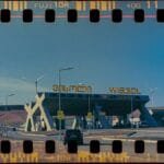 Vintage-style gas station in Gori, Georgia with wind turbines and cars under clear skies.