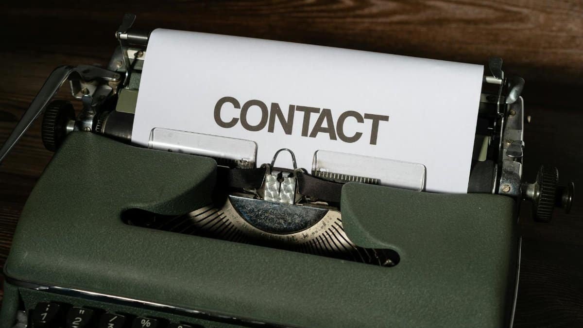 Close-up of a vintage typewriter with a white paper sheet displaying the word 'CONTACT' in bold text.