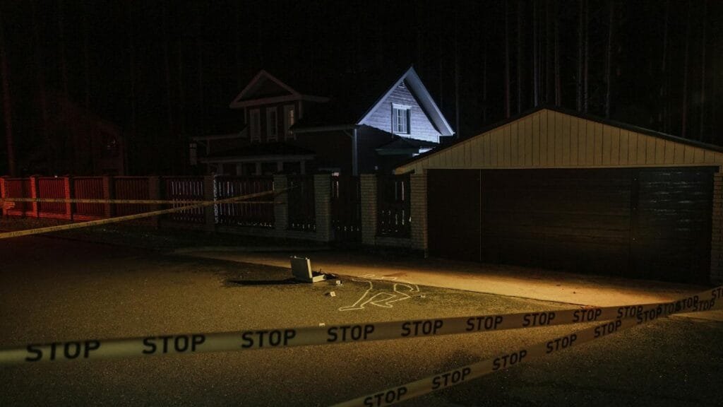 A night-time suburban crime scene with forensic evidence marked on pavement.