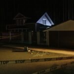 A night-time suburban crime scene with forensic evidence marked on pavement.