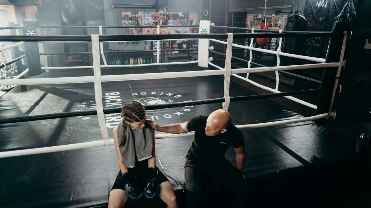 Female boxer receiving encouragement from coach in the boxing ring setting.