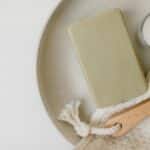 A flat lay of soap, candle, brush, and cloth for a calming self-care routine.