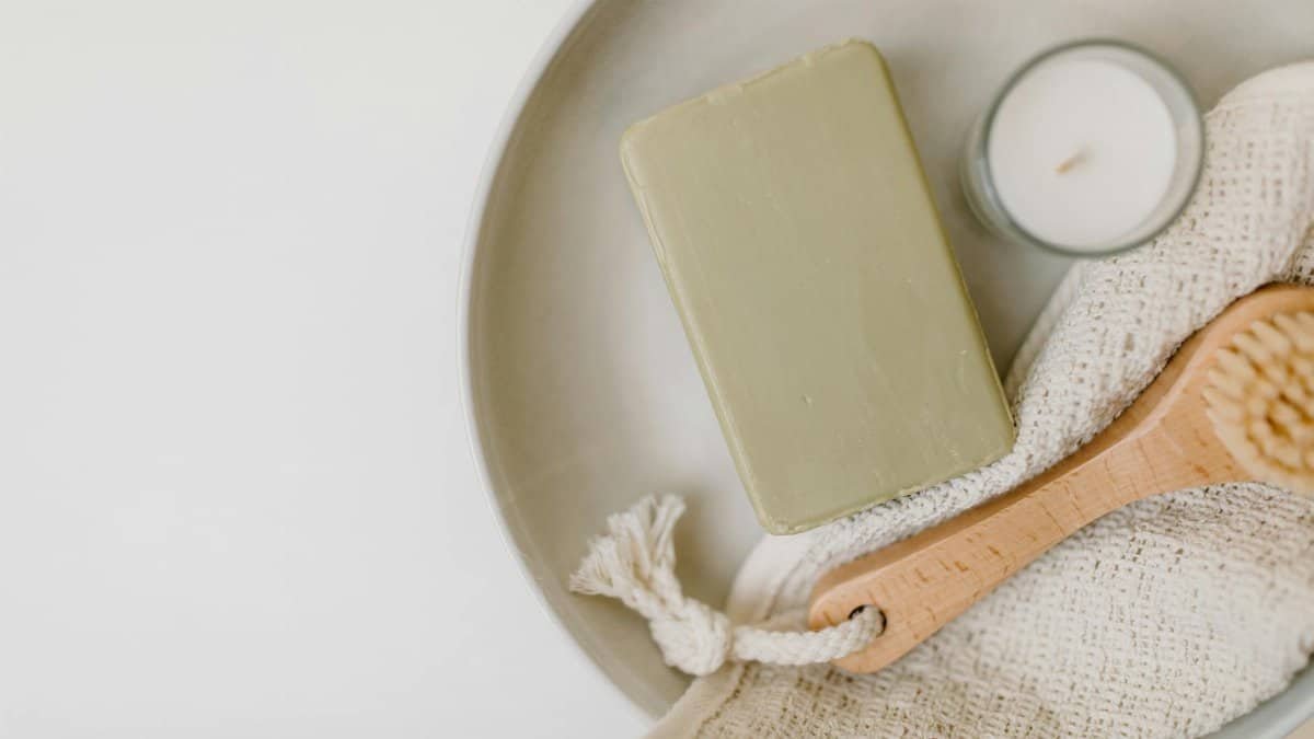 A flat lay of soap, candle, brush, and cloth for a calming self-care routine.