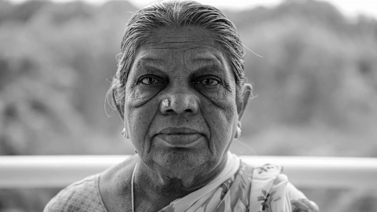 Expressive black and white portrait of an elderly woman outdoors, captured in Bengaluru, India.