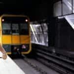 Railway staff in safety vest on platform as train arrives at Sydney station.