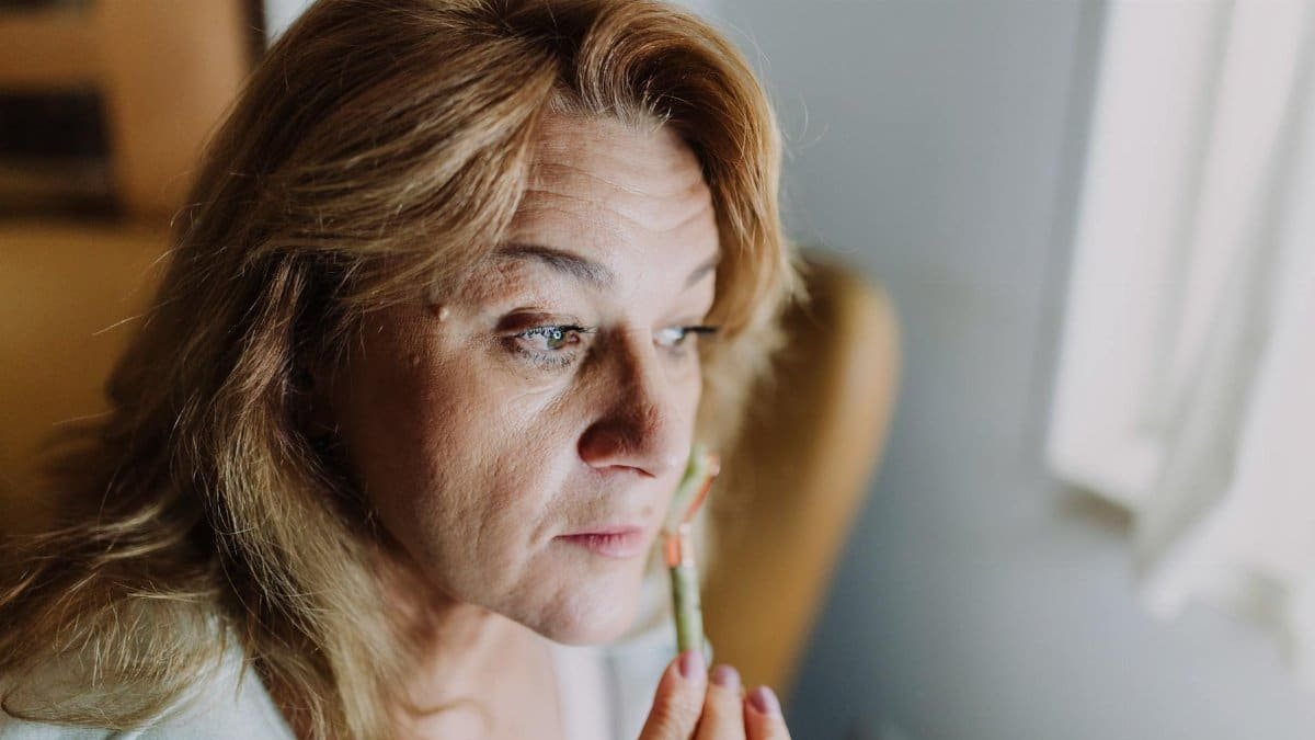 A woman applying a skincare product indoors, focusing on relaxation and self-care.
