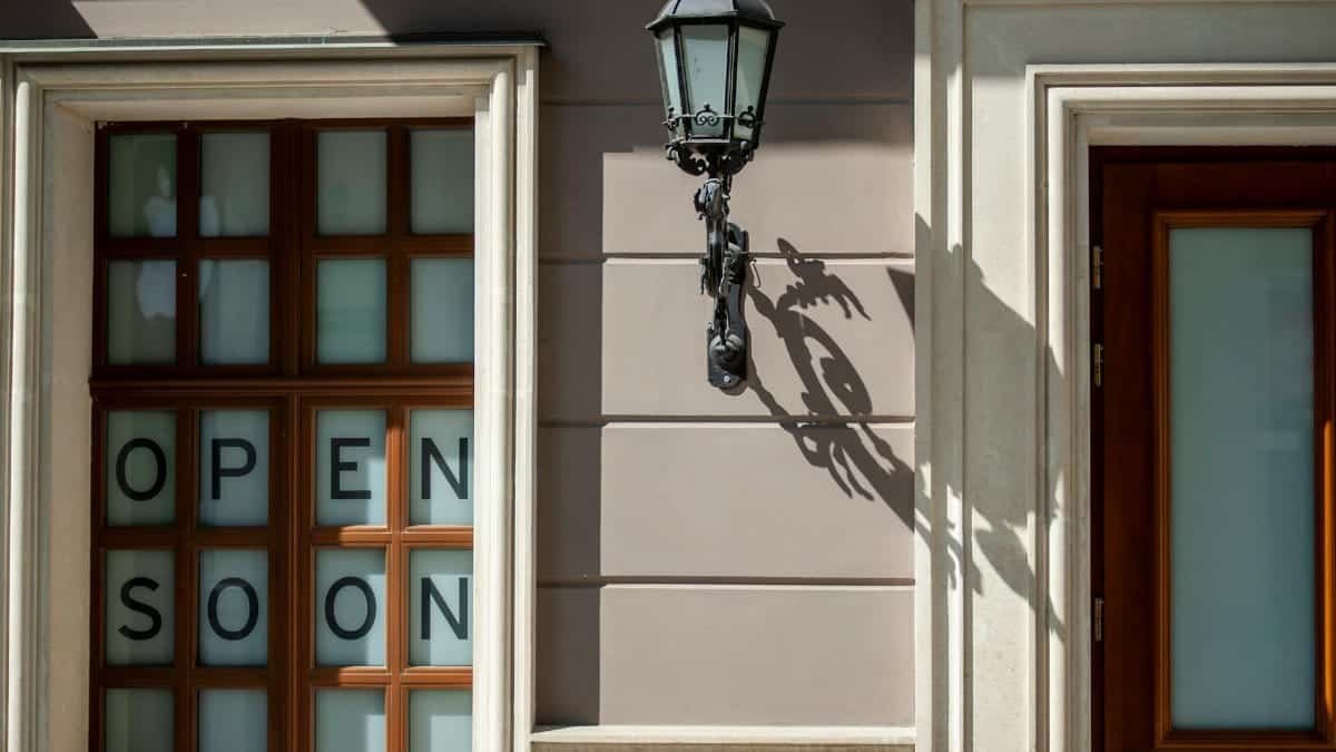 Charming facade in Lviv, featuring wooden windows and a classic lantern casting a shadow. "Open soon" sign adds intrigue.