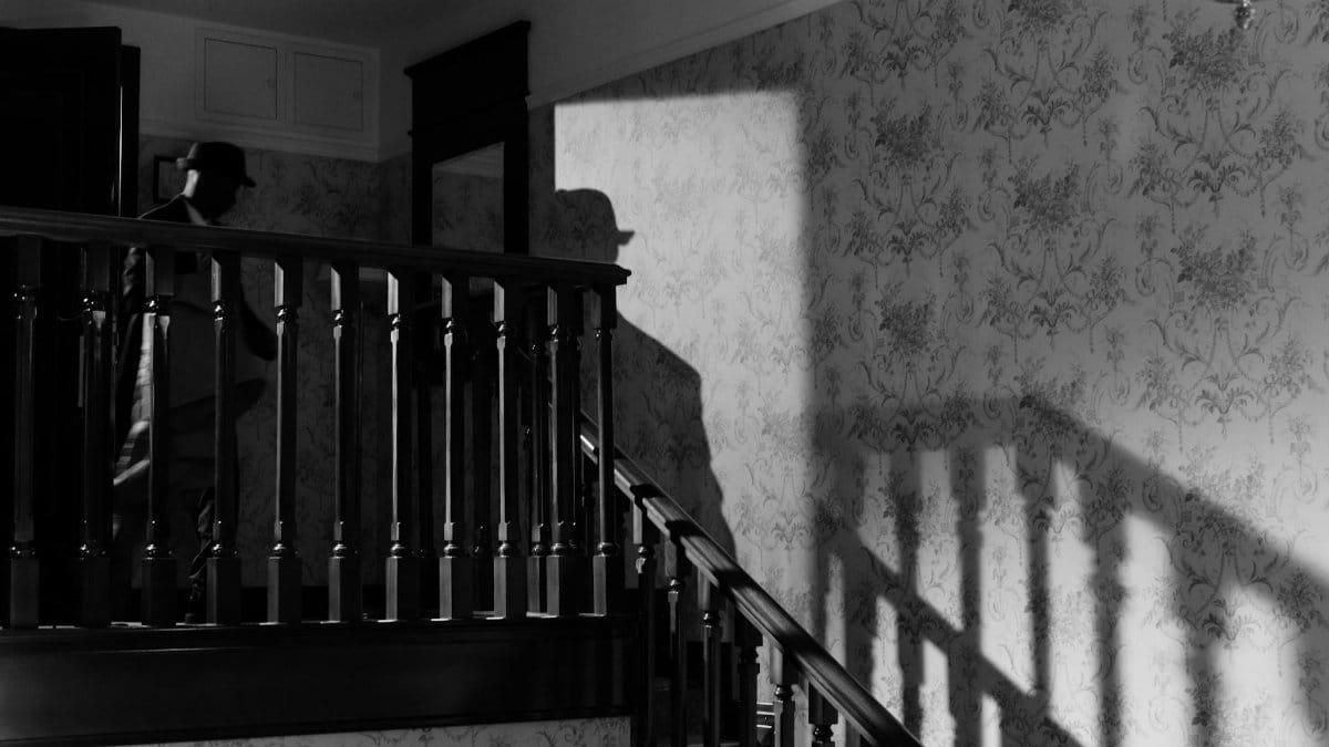 A mysterious noir scene with a detective's shadow on a vintage staircase.