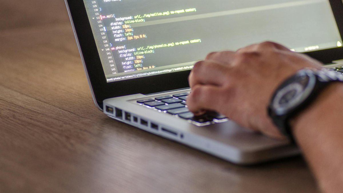 A close-up shot of a person coding on a laptop, focusing on the hands and screen.