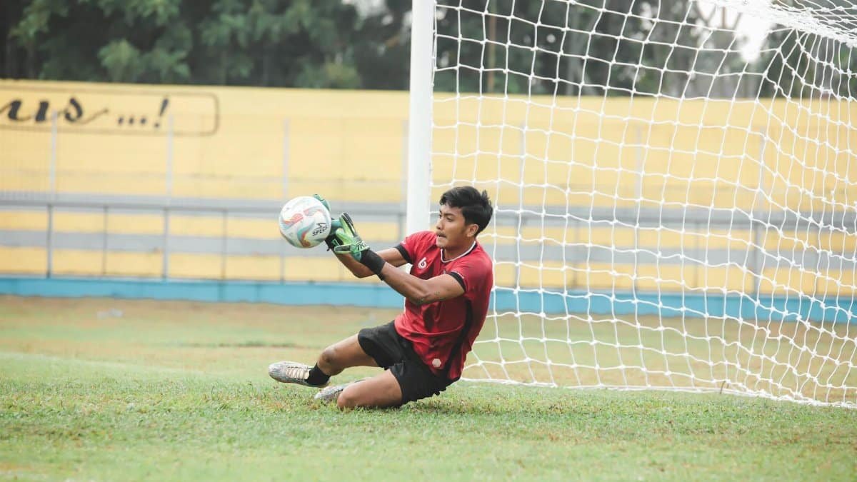 A goalkeeper in action saving the ball during a soccer match on a field.