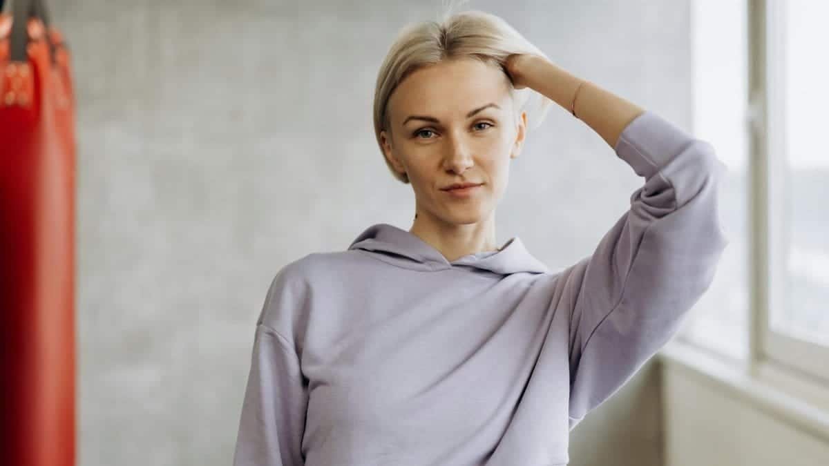 Confident woman in casual athletic wear posing indoors with natural light.