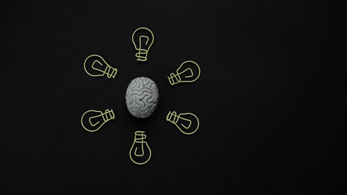Conceptual photo of a brain surrounded by light bulb clips on black background.