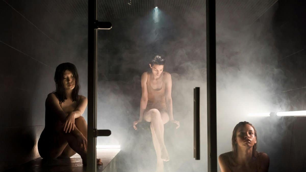 Three women enjoying the calming atmosphere of a steam-filled sauna for relaxation and wellness.